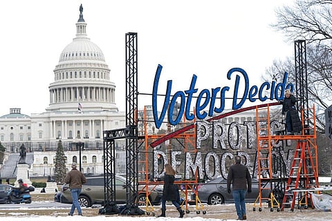 With the U.S. Capitol in the background, people walk past a sign that says say, 'Voters Decide Protect Democracy,' Jan. 6, 2022, in Washington. (File Photo | AP)