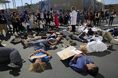 Medical workers from various countries perform a 'die-in' to protest the effect of climate change on health issues at the COP27 U.N. Climate Summit, Friday, Nov. 11, 2022. (Photo | AP)