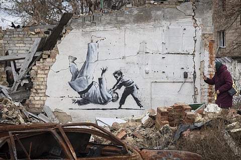 'Putin is a Judo Practitioner': A woman takes a picture of an artwork on a destroyed by fightings building in Borodyanka, Kyiv region, Ukraine, Sunday, Nov. 13, 2022. (Photo | AP)