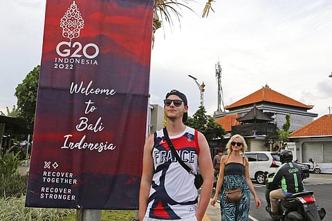 Tourists walk past a G20 banner in Nusa Dua, Bali, Indonesia (Photo | AP)