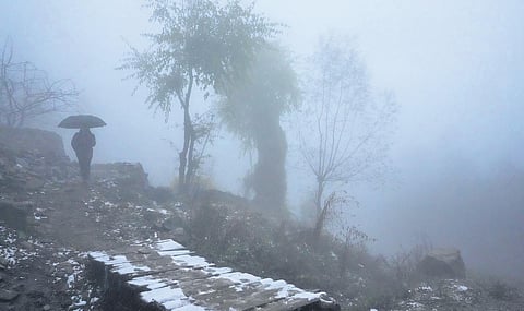 A man walks amid foggy weather and a light snowfall on the outskirts of Srinagar| PTI