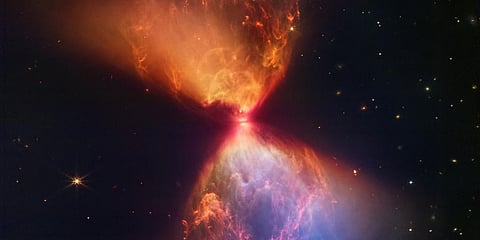 The James Webb Space Telescope unveiled an image of an ethereal hourglass of orange and blue dust being shot out from a newly forming star at its centre. (Photo | AFP)