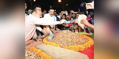 CM Basavaraj Bommai gives groundnuts to customers at the Kadalekai Parishe in Basavanagudi on Sunday evening
