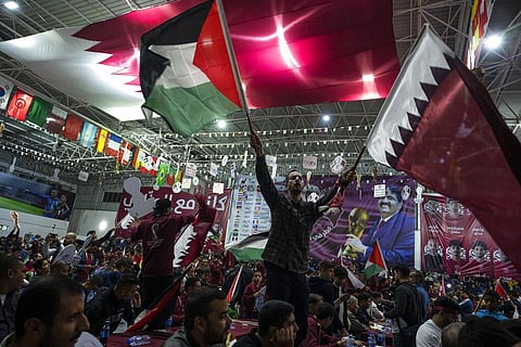 Palestinian soccer fans wave Qatari and Palestinian flags as they watch a live broadcast of the 2022 World Cup opening match between Qatar and Ecuador, Nov. 20, 2022. (Photo | AP)