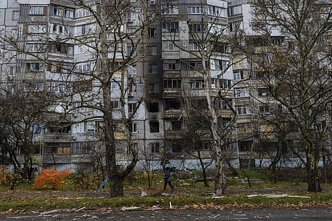 A woman walks past a recently damaged building due to a Russian strike in Kherson, Nov. 25, 2022. (Photo | AP)