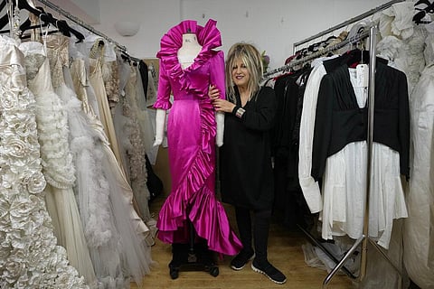 British designer Elizabeth Emanuel stands beside a replica of an evening gown she designed for the then Lady Diana Spencer | AP