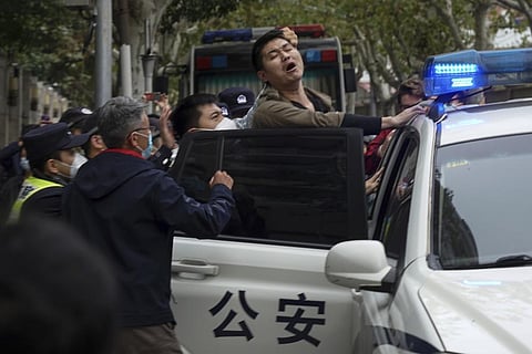 In this photo taken on Nov. 27, 2022, a protester reacts as he is arrested by policemen during a protest on a street in Shanghai, China. (Photo | AP)