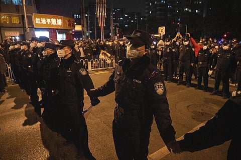 Chinese policemen form a line to stop protesters marching in Beijing. (Photo | AP)
