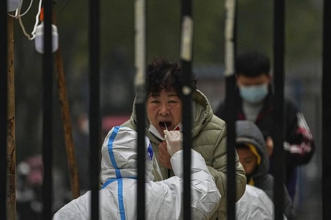 A woman has her routine COVID-19 test at a coronavirus testing site setup inside a residential compound in Beijing, Nov. 24, 2022. (Photo | AP)