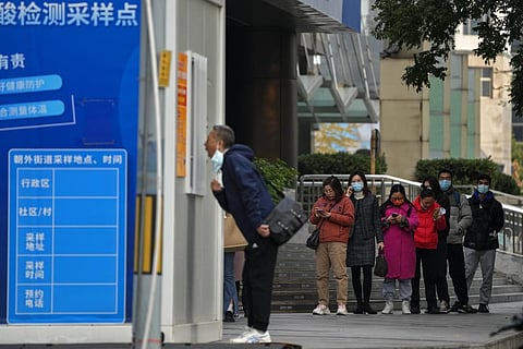 People wait in line for their routine COVID-19 throat swabs at a coronavirus testing site setup along a pedestrian walkway in Beijing, Wednesday, Nov. 2, 2022. (Photo | AP)