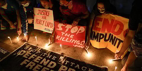 Activists light candle beside slogans as they condemn the killing of Filipino journalist Percival Mabasa during a rally in Quezon city, Philippines on Oct. 4, 2022. (File Photo | AP)