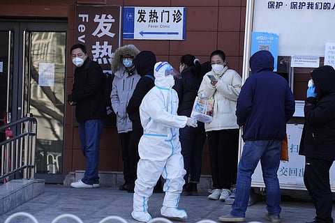A worker in protective overalls controls the line outside the fever clinic at a hospital in Beijing. (Photo | AP)