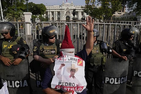 A supporter of ousted President Pedro Castillo holds his photo in front of Congress in Lima, Peru, Sunday, Dec. 11, 2022. (Photo | AP)