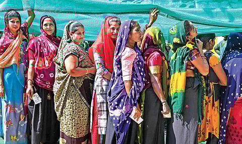 Women wait in a queue to cast their votes at a polling station during the first phase of Gujarat Assembly elections in Somnath on Thursday | PTI