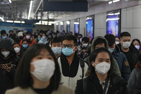 Masked commuters walk through a walkway in between two subway stations as they head to work during the morning rush hour in Beijing, Tuesday, Dec. 20, 2022. (Photo |AP)