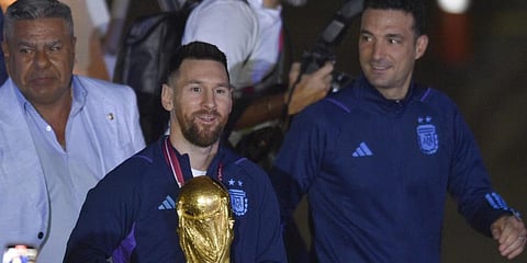 Argentina's Lionel Messi holds the FIFA World Cup trophy as he deplanes, with coach Lionel Scaloni, in Buenos Aires, Argentina, Tuesday, Dec. 20, 2022.(Photo | AP)