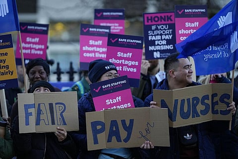Demonstrators hold up placards in support of a strike by nurses outside St Thomas' Hospital in London, on December 20, 2022. (Photo | AP)