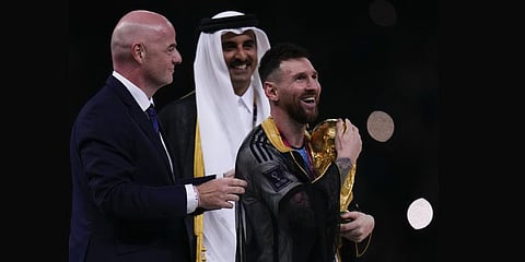 Lionel Messi holds up the trophy flanked by FIFA President Gianni Infantino, (L), and The Emir of Qatar Sheikh Tamim bin Hamad Al Thani after the World Cup final at the Lusail Stadium. (Photo | AP)