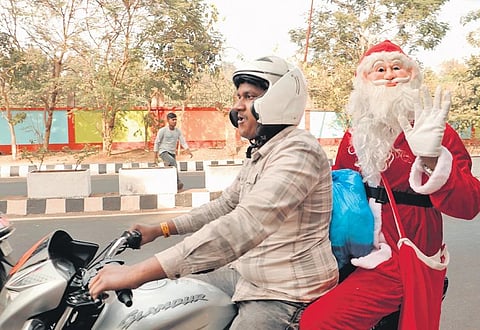 A man wearing Santa Claus costume riding pillion on a two-wheeler in Bhubaneswar on Friday | Shamim Qureshy