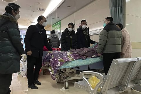 A Chinese man pulls a cloth to cover up the face of an elderly woman whose vitals flatlined as emotional relatives gather silently around her for a final farewell before her body is taken away. (AP)