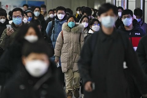 Masked commuters walk through a walkway in between two subway stations as they head to work during the morning rush hour in Beijing. (Photo | AP)