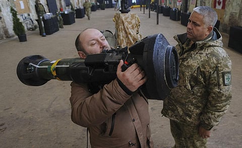 A Ukrainian serviceman shows a civilian how to operate an anti-tank weapon during the Weapon of Victory exhibition in Lviv, western Ukraine. (Photo | AP)