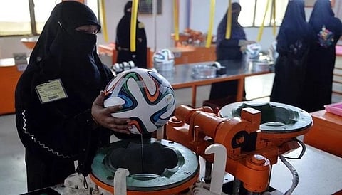 In this backdated image, a worker applies adhesives to the edges of a design on a football at a factory in Sialkot, Pakistan. (Photo | AFP)