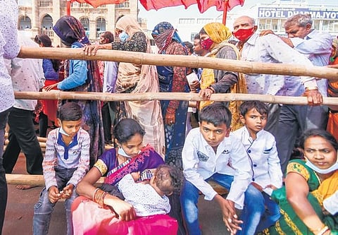 A woman feeds her baby while waiting near the queue of devotees to enter Sri Jagannath Temple for darshan of the Trinity in Puri on Friday | DEBADATTA MALLICK