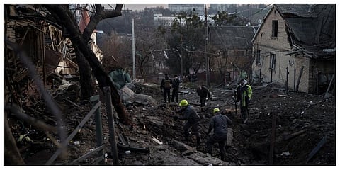 Workers inspect a crater in a residential street following a Russian attack in Kyiv. (Photo | AP)