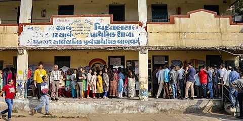 Voters wait in a queue to cast their votes at a polling booth during the second and final phase of Gujarat Assembly elections. (Photo | PTI)