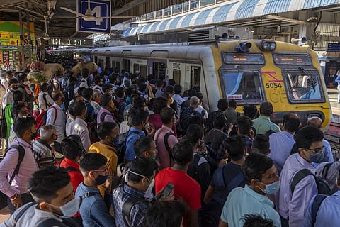 People wearing masks as a precaution against the coronavirus crowd a railway station platform as they wait to board trains in Mumbai. (Photo | AP)