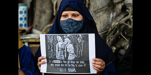 A muslim woman holds a placard during a protest against banning Muslim girls wearing hijab from attending classes at some schools in the southern Indian state of Karnataka, in Kolkata. (Photo | AP)