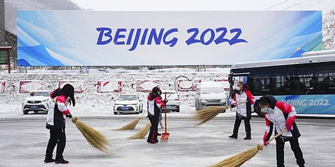 Volunteers clear snow from the bus terminal at the Zhangiiakou Media Center during the 2022 Winter Olympics.(Photo | AP)