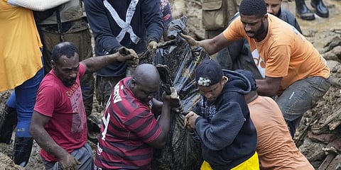 Residents and volunteers remove the body of a mudslide victim in Petropolis, Brazil, Wednesday, Feb. 16, 2022.(Photo | AP)