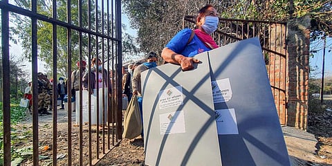 A polling official carries election materials and waits to board a bus to a polling booth, a day before the Punjab Assembly elections at Polo Ground, in Amritsar. (Photo| PTI)