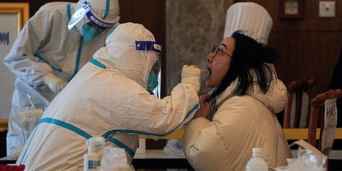 A medical worker collects a sample from a reporter taking part in the Beijing Winter Olympics torch relay activities at a coronavirus test site in Beijing, Wednesday, Feb. 2, 2022. (Photo | AP)