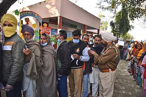People stand in a queue to cast their vote at polling station near the India-Pakistan border for the Punjab State Assembly elections in the village of Bachiwind. (Photo | AP)