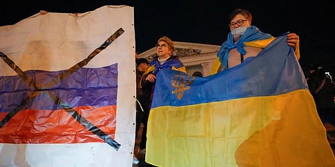Ukrainians hold up their country's flag, right, as they attend a patriotic action 'Mariupol is Ukraine' in Mariupol, Ukraine, (Photo | AP)