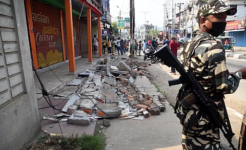 A CRPF personnel stand guards near an earthquake-damaged building at Bhetapara in Guwahati. (Photo | PTI)