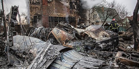 A Ukrainian firefighter walks between at fragments of a downed aircraft seen in in Kyiv, Ukraine, Friday, Feb. 25, 2022. (Photo | AP)