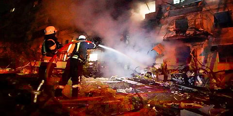 Firefighters hose down burning debris in front of a damaged building following a rocket attack on the city of Kyiv, Ukraine. (Photo | AP)
