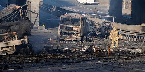 A Ukrainian soldier walks past debris of a burning military truck, on a street in Kyiv, Ukraine. (Photo | AP)