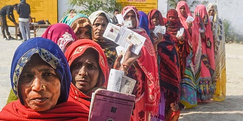 Women show their identification cards as they wait in a queue at a polling station to cast their votes in the Uttar Pradesh Assembly polls. (Photo | PTI)