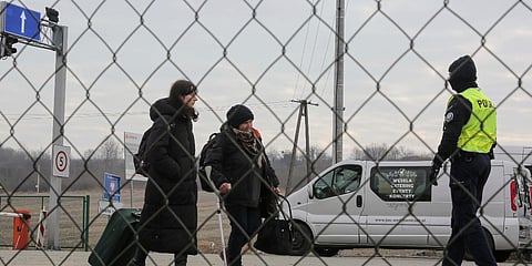 Police officers directs refugees fleeing conflict in Ukraine as they arrive, at the Medyka border crossing, in Poland. (Photo| AP)