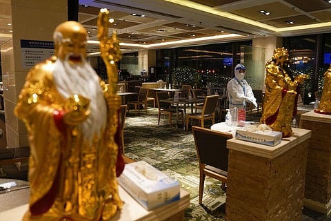 A waitress wearing a protective suit stands at a restaurant in a hotel at the 2022 Winter Olympics, Thursday, Feb. 3, 2022, in Beijing. (Photo | AP)