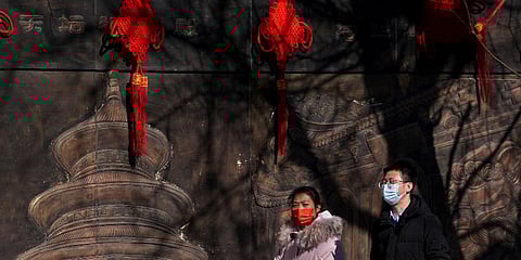 Residents wearing face masks to help protect from the coronavirus walk by a mural decorated with Lunar New Year decorations in Beijing, Tuesday, Feb. 8, 2022. (Photo | AP)