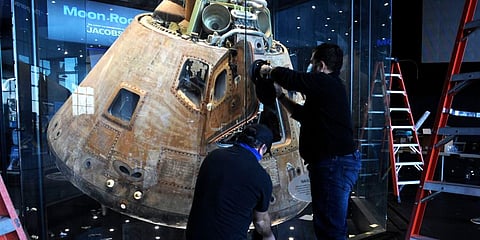 Workers open the glass case enclosing the Apollo 16 lunar capsule at the U.S. Space and Rocket Center in Huntsville, Ala., on Tuesday, Feb. 1, 2022. (Photo | AP)