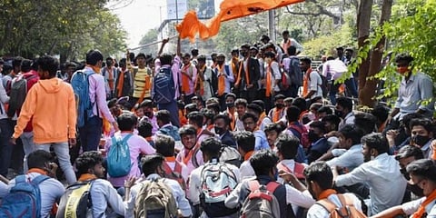 Students wearing saffron shawl block a road during protest over 'Hijab' controversy, in Shivamogga. (Photo | PTI)