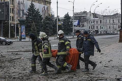 Ukrainian emergency service personnel carry a body of a victim following shelling that hit the City Hall building in Kharkiv. (Photo | AP)