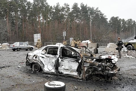 Ukrainian servicemen and volunteers of Ukraine's Territorial Defense Forces stand behind a damaged car at a checkpoint in Brovary, outside Kyiv, Ukraine. (Photo |AP)